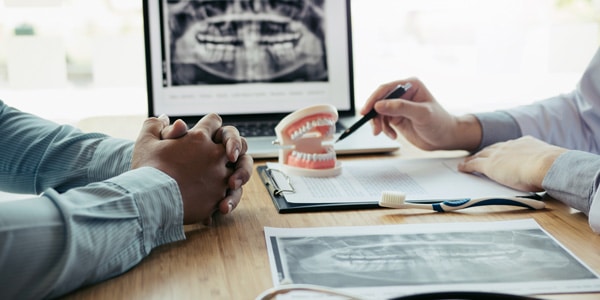 a dentist and a client discussing a dental procedure while examining details on a table